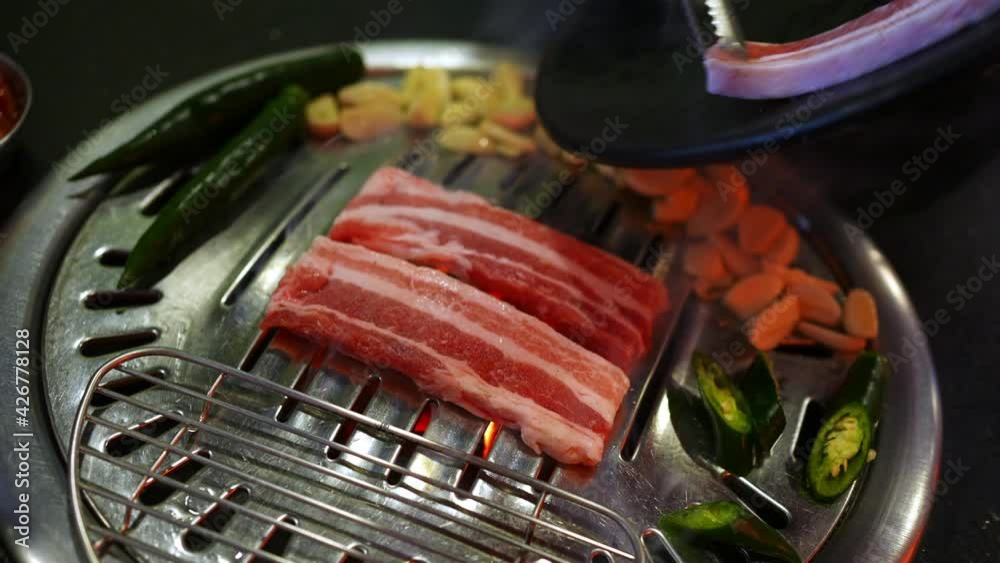 Chef hand cooking smoked grilled pork belly meat with garlic and green
