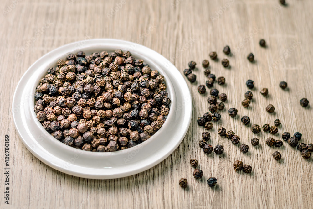 Black pepper seeds in a cup on the table, spices used in cooking Black pepper seeds in a cup on the table, spices used in cooking