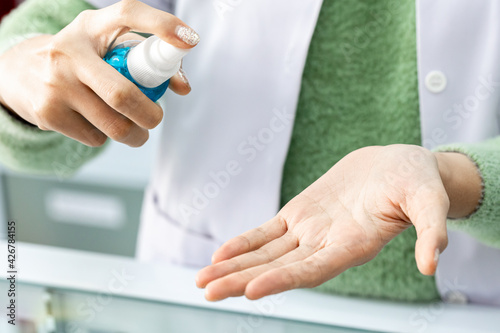 Closeup of Asian Medical Personnel hand holding Spray for wash hand sanitizer before work for Protect herself and her patients from COVID19. 