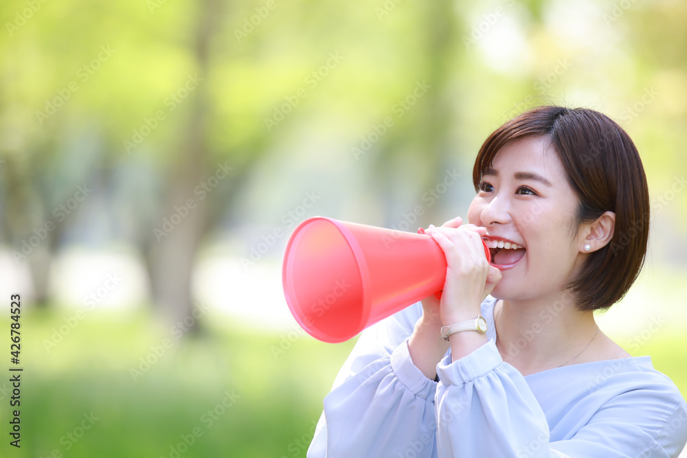 メガホンを持ち声援を送る女性社員 メガホンを持ち声援を送る女性社員