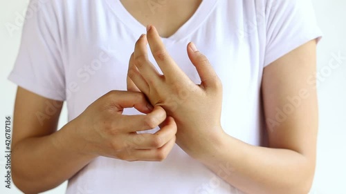 Young woman is scratching her hand on the white background.