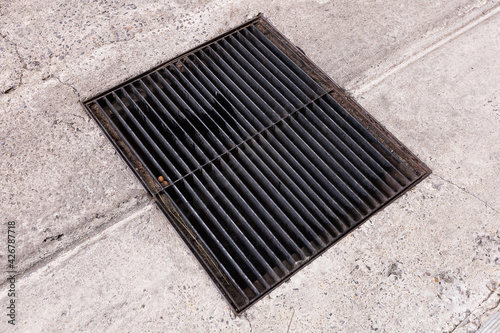 Old steel drainage grating on road