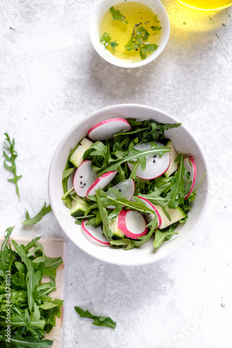 Fresh green spring salad with arugula and radish at light background
