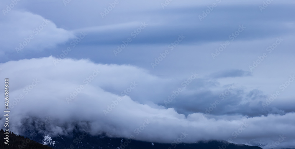 Panoramic View of Puffy Clouds over the Canadian Mountain Landscape. Colorful Winter Sunset Cloudscape Background. Taken between Squamish and Whistler, British Columbia, Canada.