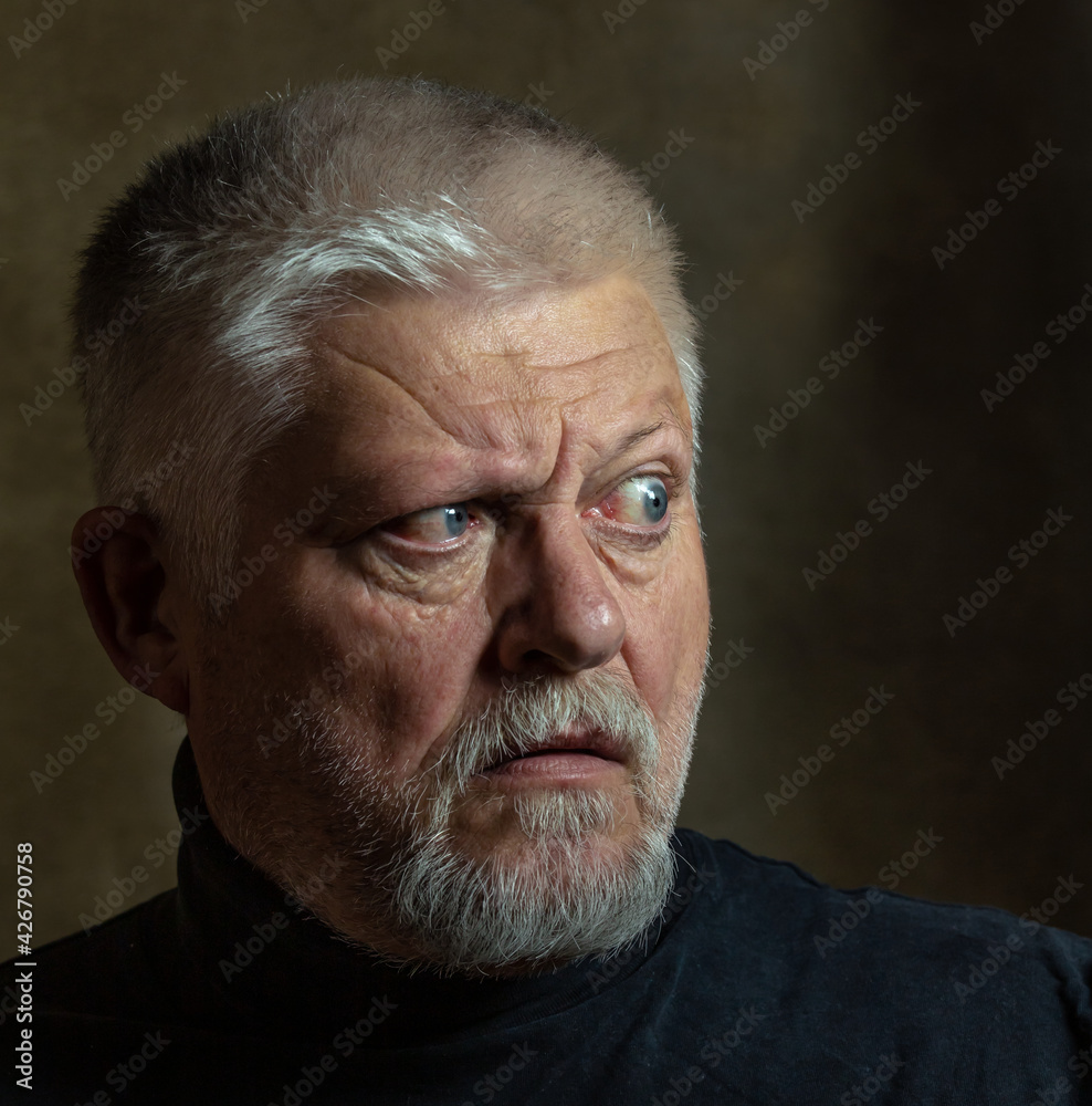 Obraz premium Portrait of an elderly man in classic Rembrandt light. The person looks to the side, startled.