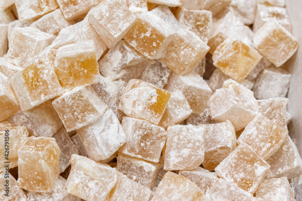 Heap of sweet cubes in powdered sugar. Turkish delight or lokum is a confections based on a gel of starch and sugar. Selective focus. Heap of sweet cubes in powdered sugar. Turkish delight or lokum is a confections based on a gel of starch and sugar. Selective focus.