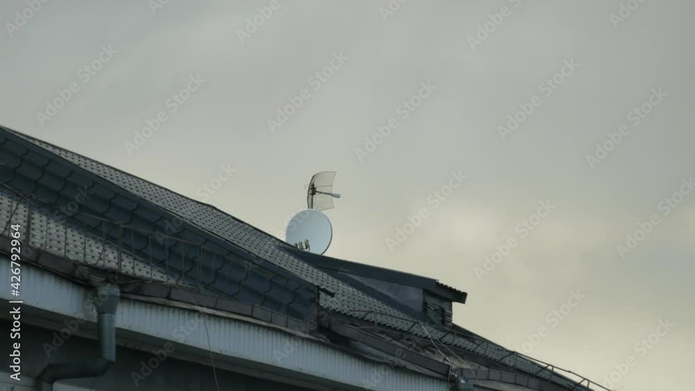 Antennas receiving a television signal on the roof of a building against the backdrop of a cloudy sky and gray clouds. Antennas receiving a television signal on the roof of a building against the backdrop of a cloudy sky and gray clouds.