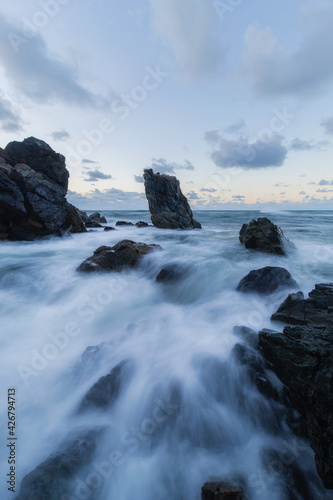 Wave water coming in between rock formation in the shore.