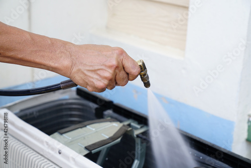 Engineer or repairman fixing and cleaning air conditioner unit by high pressure water jet
