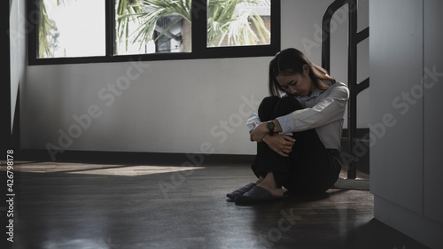 Lonely young woman sitting on the floor in a dark room with feeling sad and depressed.
