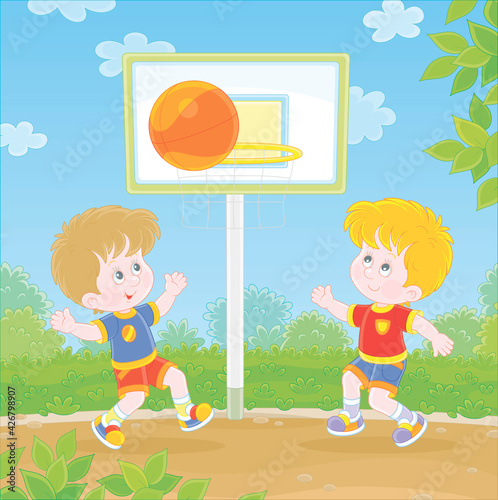 Cheerful little kids playing basketball with a big orange ball on a sports ground in a green park on summer vacations, vector cartoon illustration