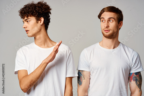 Two cheerful friends in t-shirts stand side by side isolated background joy