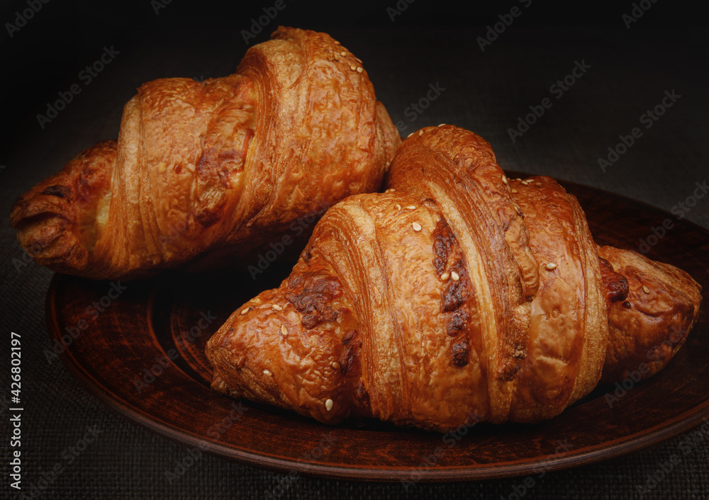Two beautiful croissants on a clay dish. Two beautiful croissants on a clay dish.