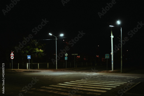 Pedestrian crossing at night in the illumination of street lamps in a post-Soviet city, devastation