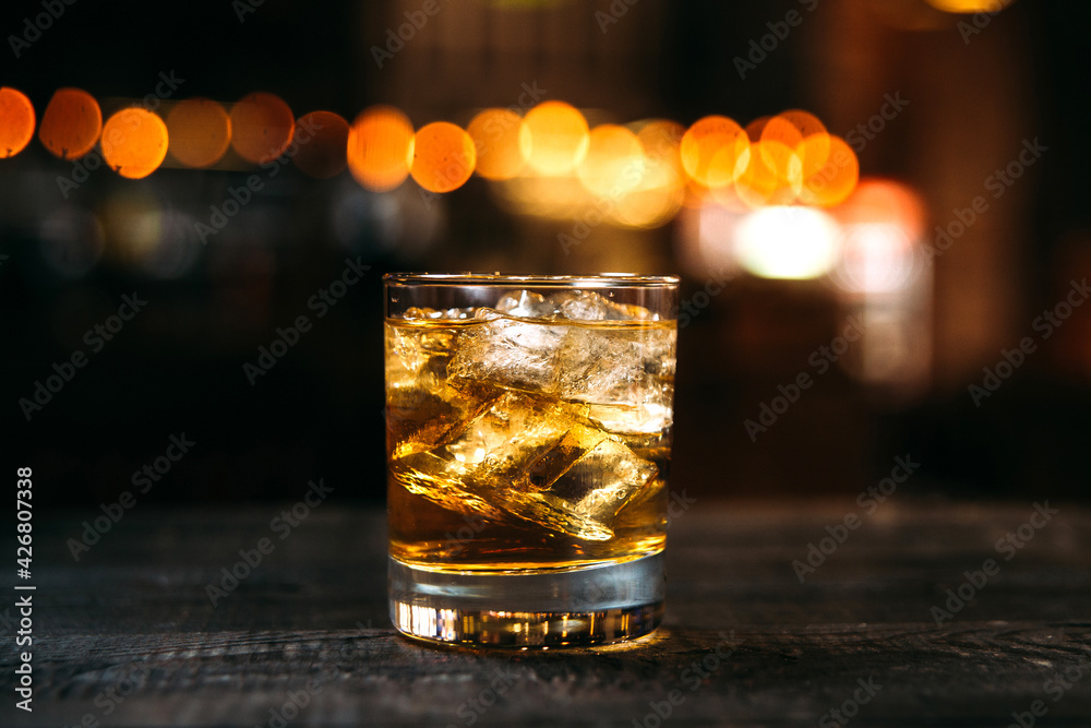 Whiskey old fashioned cocktail on the bar desk with blurry background