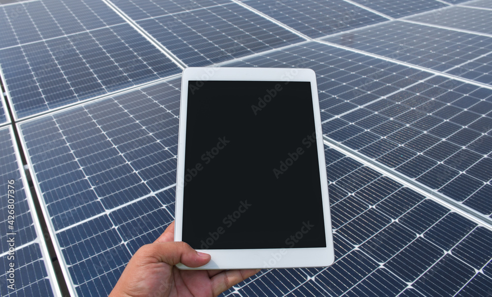 A hand hold tablet with a background is a solar cell that generates electricity from sunlight, an alternative energy, renewable energy concept.