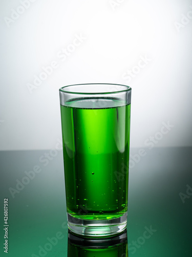 tall transparent glass with green tarragon lemonade on a light background