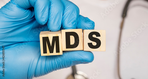 MDS Myelo dysplastic syndrome - word from wooden blocks with letters holding by a doctor's hands in medical protective gloves. Medical concept.