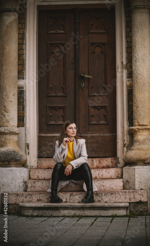 Influencer sitting on the stairs of an old building and posing with hand on her chin. © dusanpetkovic1