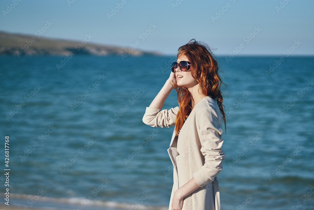 red-haired traveler in a coat and a t-shirt on the beach near the sea summer vacation red-haired traveler in a coat and a t-shirt on the beach near the sea summer vacation