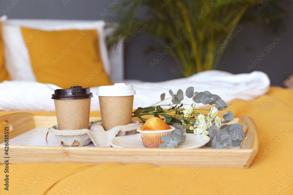 breakfast in bed for two. two paper takana with coffee cupcake. white and orange color