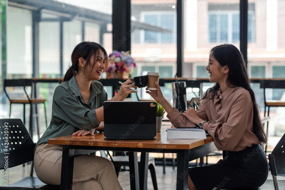 Happy two young woman success in work holding coffee cup at the café. Happy two young woman success in work holding coffee cup at the café.