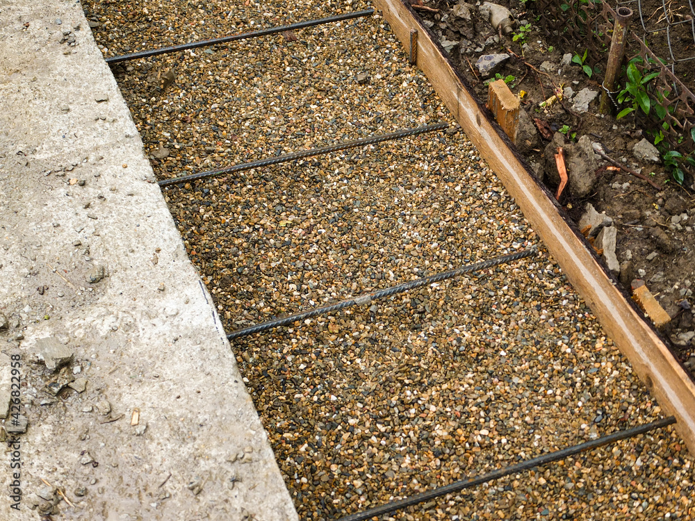 Preparation for concreting blind area around building. Base of blind area is covered with gravel. Armature is tied together with knitting wire. Formwork was installed along entire length of blind area