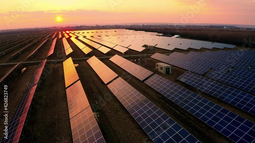 Aerial Top view of a Solar Power Station at Sunset. Flying from above Solar panels. Concept of Renewable Energy, Green energy. Sun generates energy in Europe 