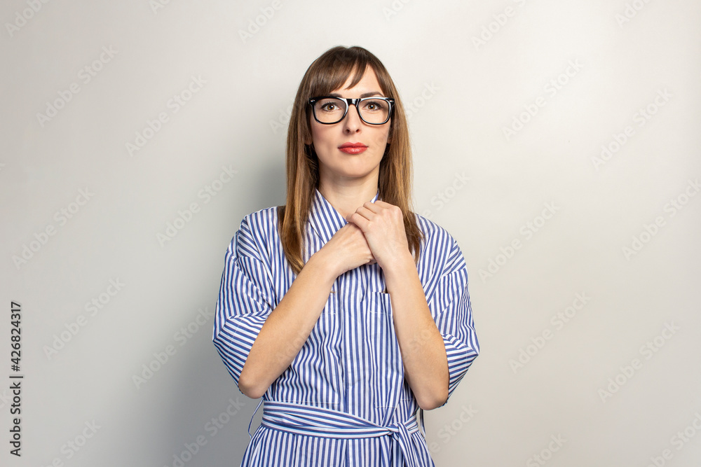 young girl in a blue dress holds her hands on her chest on a light background. Concept of summer, vacation, travel. Banner young girl in a blue dress holds her hands on her chest on a light background. Concept of summer, vacation, travel. Banner