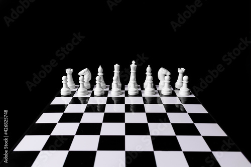 Row of white chess before game on black-white board in the dark