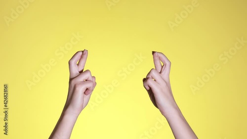 Woman hands keeping fingers crossed, waiting for special moment, making wish isolated over pastel yellow background. Copy space for advertisement. With place text or image promotional content