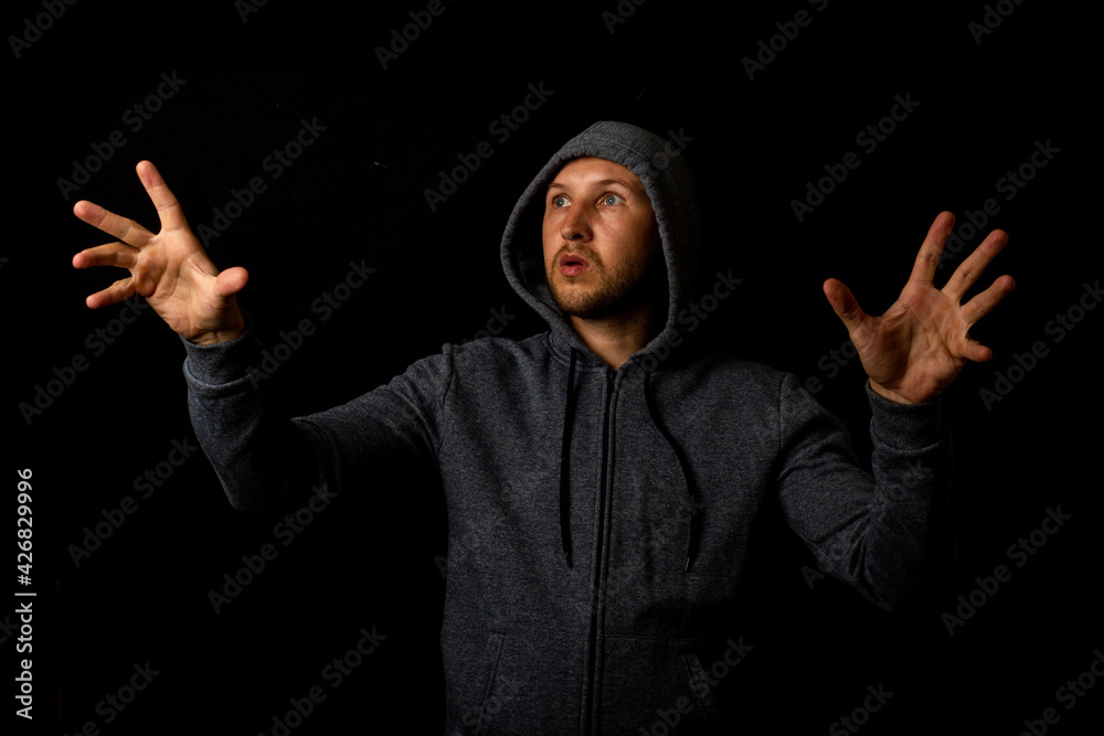 Man in a hood is touching something on a dark background Man in a hood is touching something on a dark background