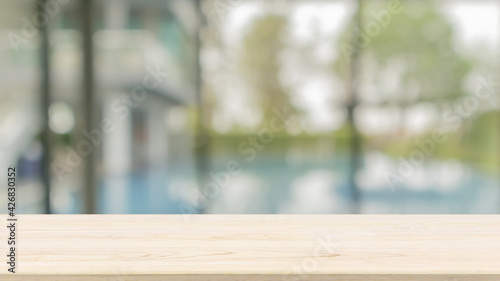Empty wood table top with blurred window and swimming pool background for product display