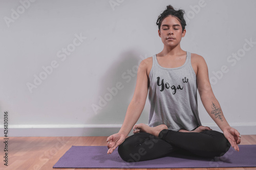 Young woman meditating on yoga mat in studio