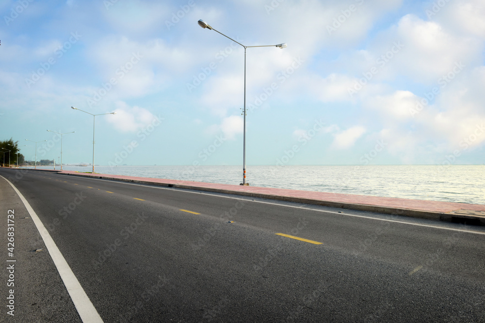Empty asphalt road with marking line for given direction and sea landscape. Transportation concept and summer travel holiday idea Empty asphalt road with marking line for given direction and sea landscape. Transportation concept and summer travel holiday idea