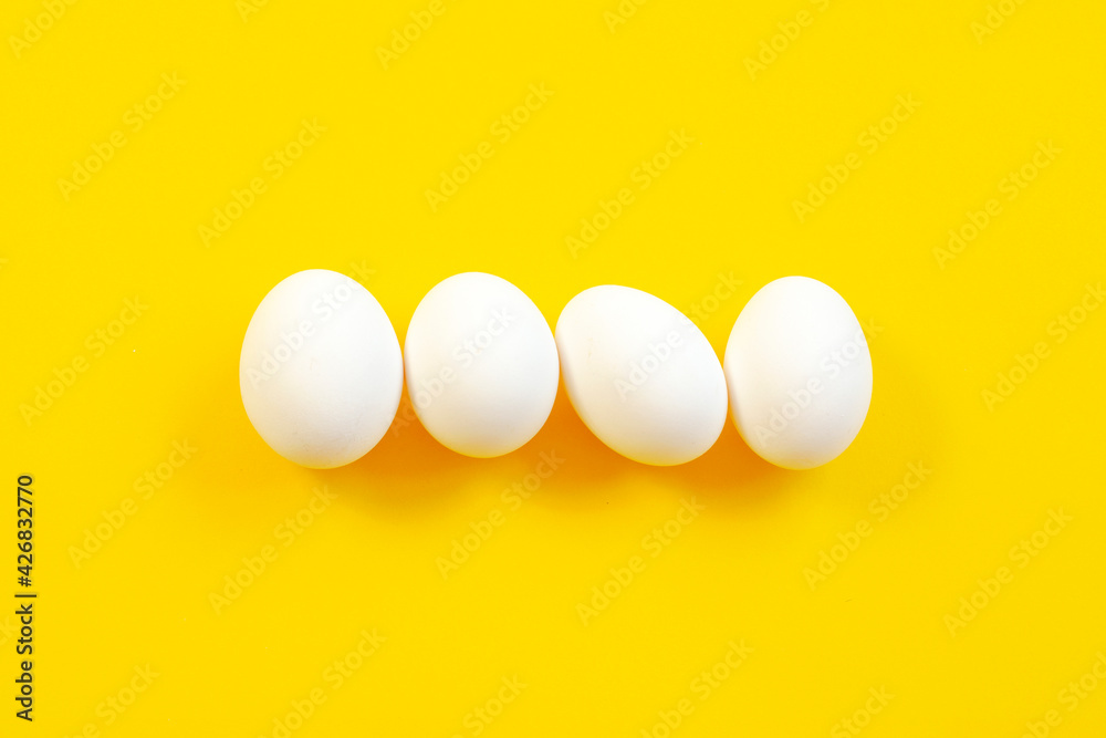 White eggs on a yellow background in the center, top view, copy space. Raw eggs on a yellow background, copy space, top view. White egg on a yellow background, top view. Design, minimalism, fine art. White eggs on a yellow background in the center, top view, copy space. Raw eggs on a yellow background, copy space, top view. White egg on a yellow background, top view. Design, minimalism, fine art.