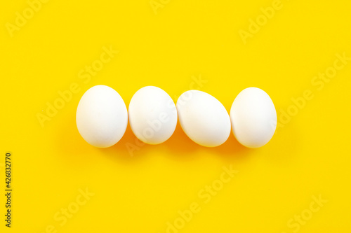 White eggs on a yellow background in the center, top view, copy space. Raw eggs on a yellow background, copy space, top view. White egg on a yellow background, top view. Design, minimalism, fine art.