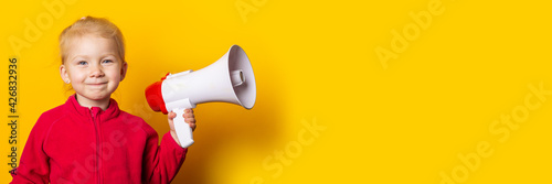 smiling child girl holding a megaphone on a bright yellow background. Banner.