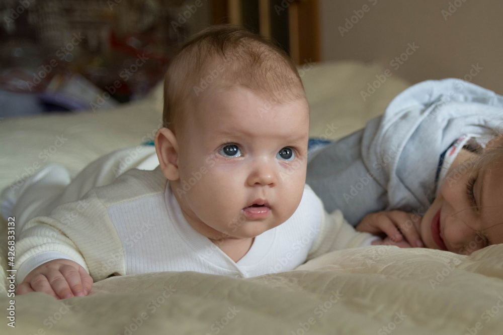The girls are lying on a light bedspread. The girls are lying on a light bedspread.