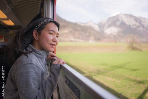 train travel getaway - lifestyle portrait of young happy and beautiful Asian Chinese woman traveling on railway looking through window relaxed and cheerful © TheVisualsYouNeed