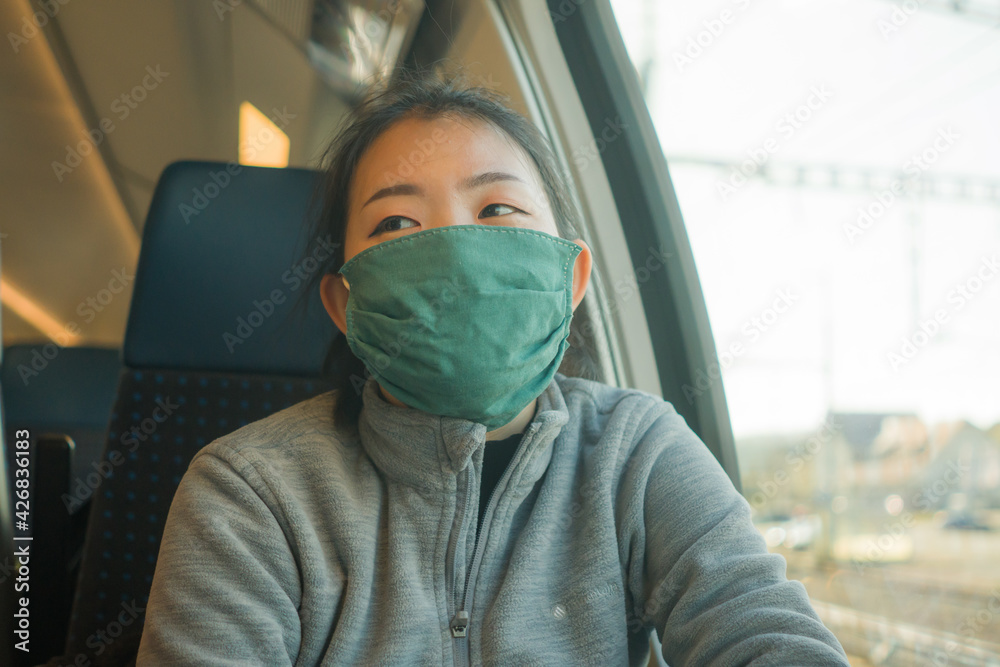 train travel during covid19 - young happy and cute Asian Japanese woman in face mask traveling on railcar enjoying landscape through the window train travel during covid19 - young happy and cute Asian Japanese woman in face mask traveling on railcar enjoying landscape through the window