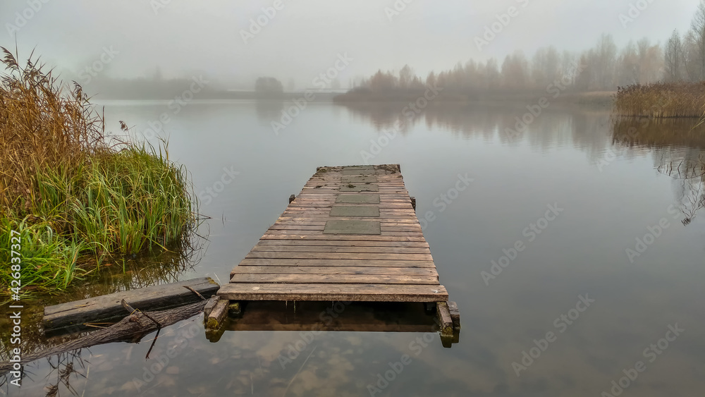 Floating pier on the lake shrouded in fog in autumn