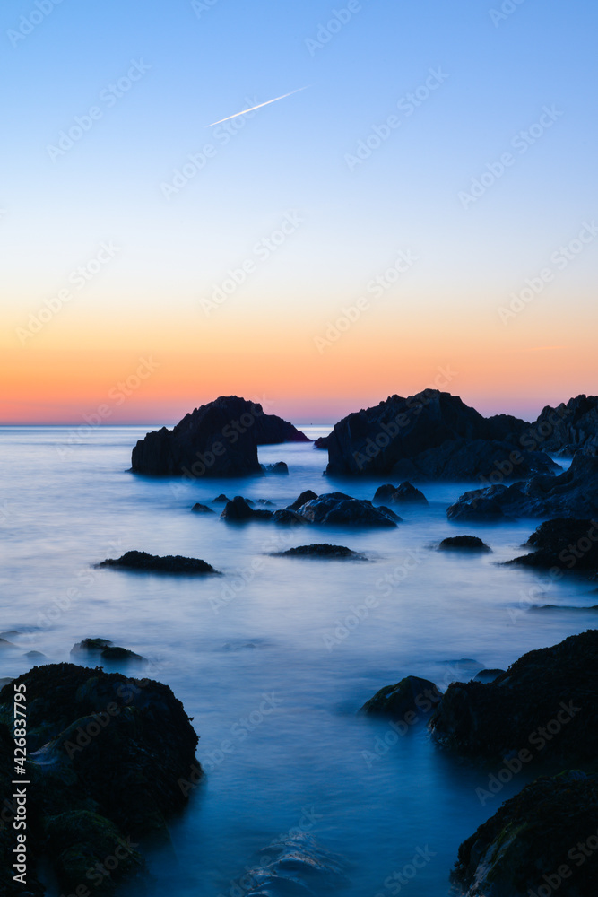 Relaxing sunset view of the sea in slow shutter over rocks