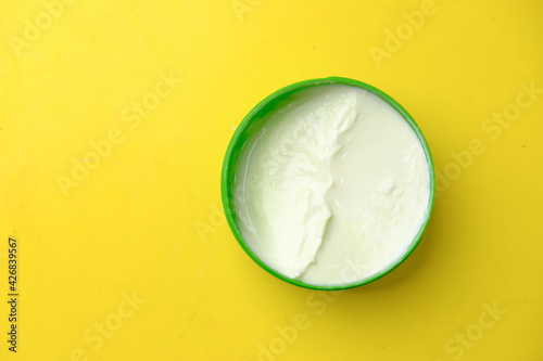 Close up of beauty cream in a container on yellow background 