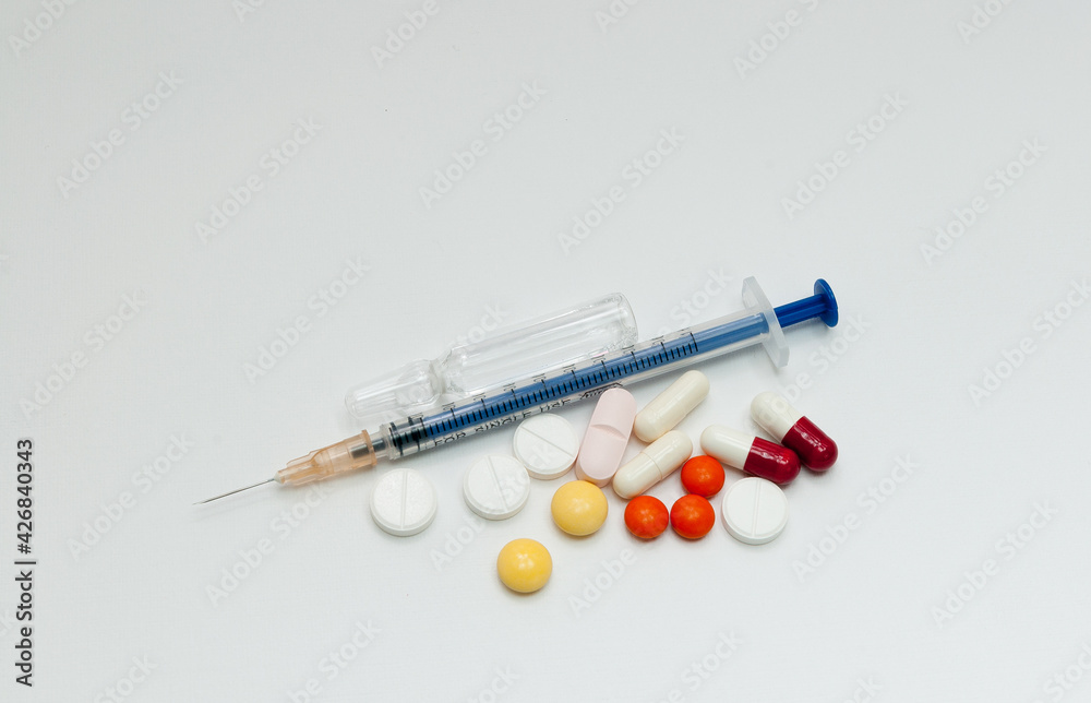 syringe with ampoules and capsules on white background syringe with ampoules and capsules on white background