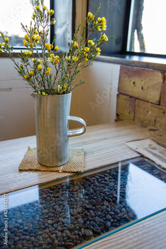 Coffee beans under the glass and flowers on the desk