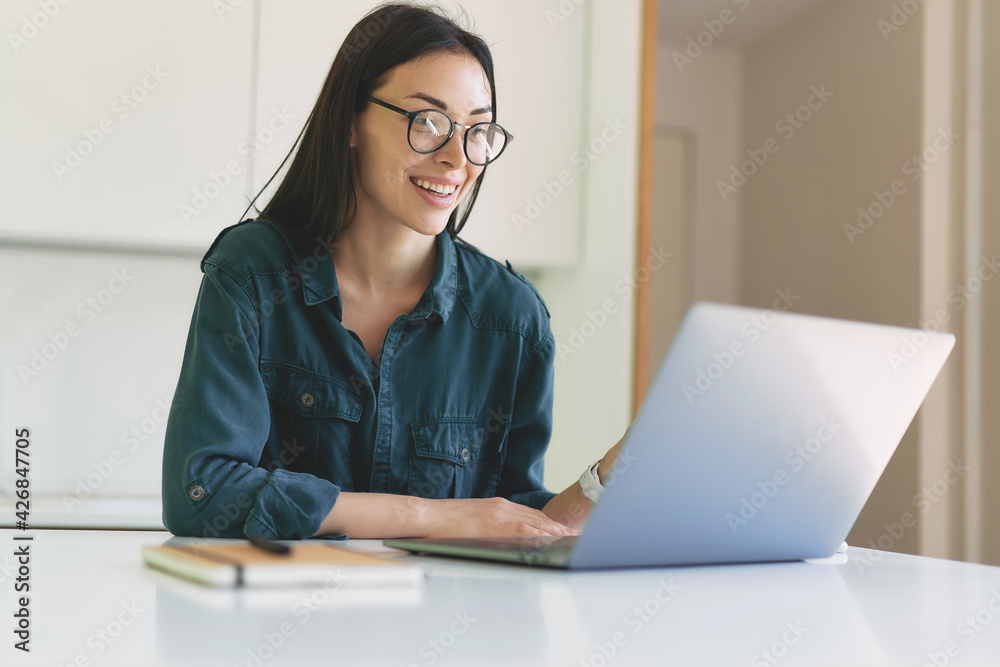 Smiling business woman working from home with laptop and notebook