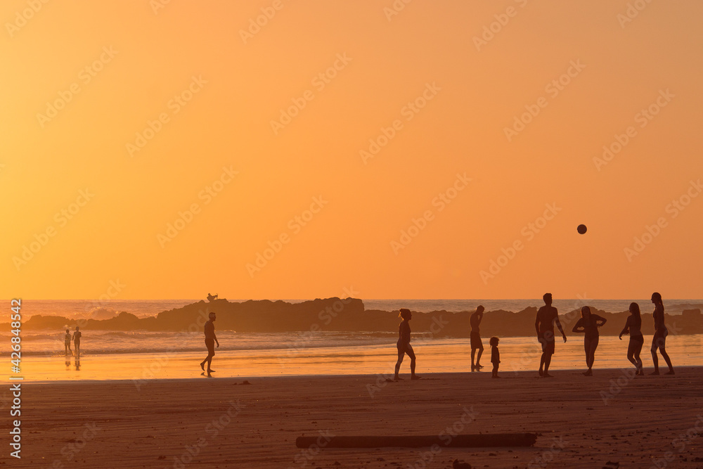 Group of friends and family playing and having fun at sunset on the beach Group of friends and family playing and having fun at sunset on the beach