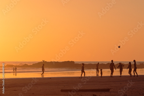 Group of friends and family playing and having fun at sunset on the beach