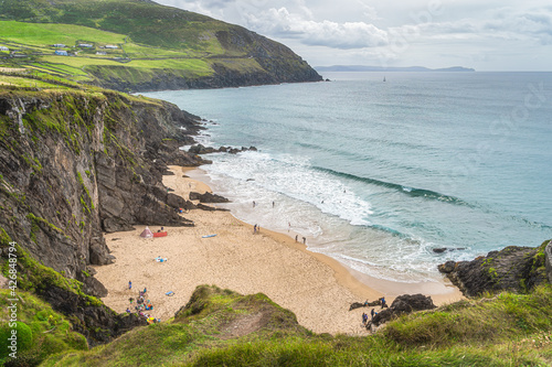 People swimming in turquoise coloured see and families relaxing on Coumeenoole Beach hidden between cliffs, Dingle, Wild Atlantic Way, Kerry, Ireland photo